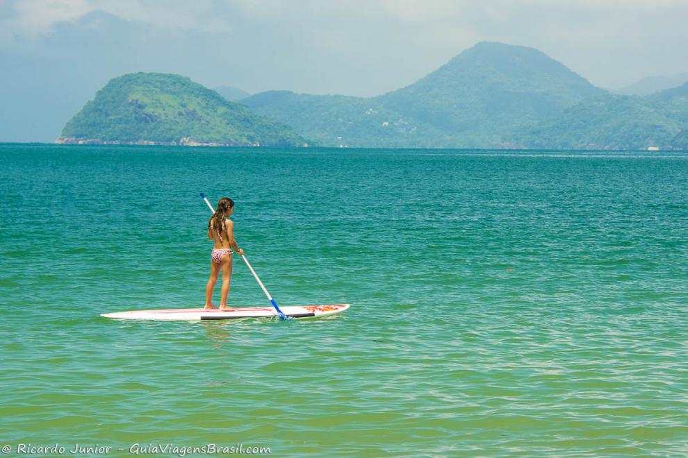 Imagem de uma menina praticando standup paddle na Praia da Almada.